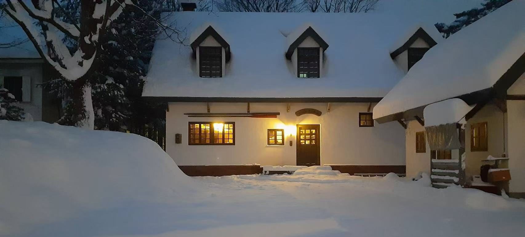 雪に覆われた白馬村の宿泊施設Maykiss（開業準備中）の夕暮れの外観
